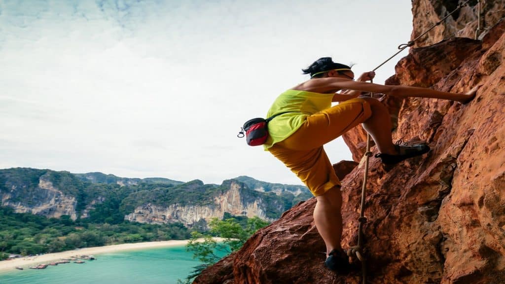 woman rock climber climbing on seaside cliff