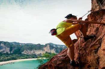 woman rock climber climbing on seaside cliff